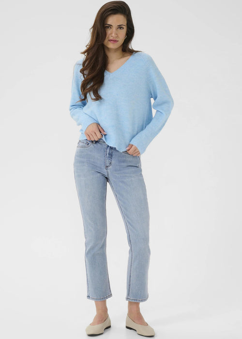 Woman wearing a light blue sweater and jeans on a white background