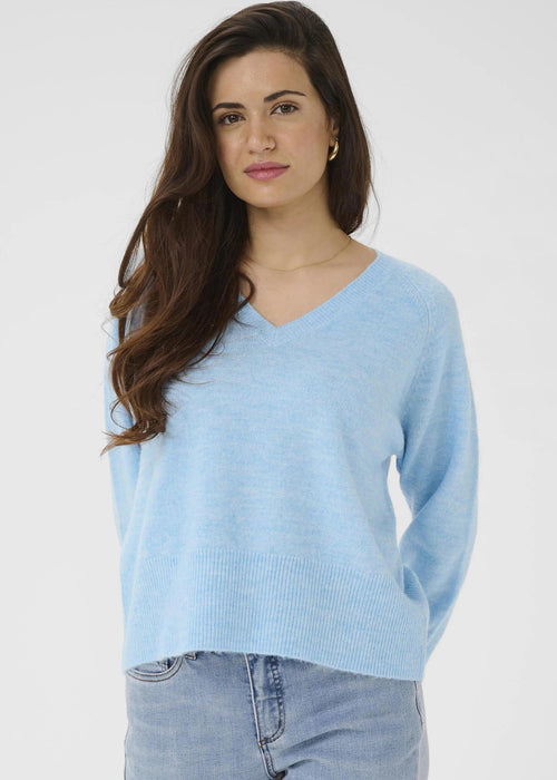 Woman wearing a light blue sweater and jeans on a white background