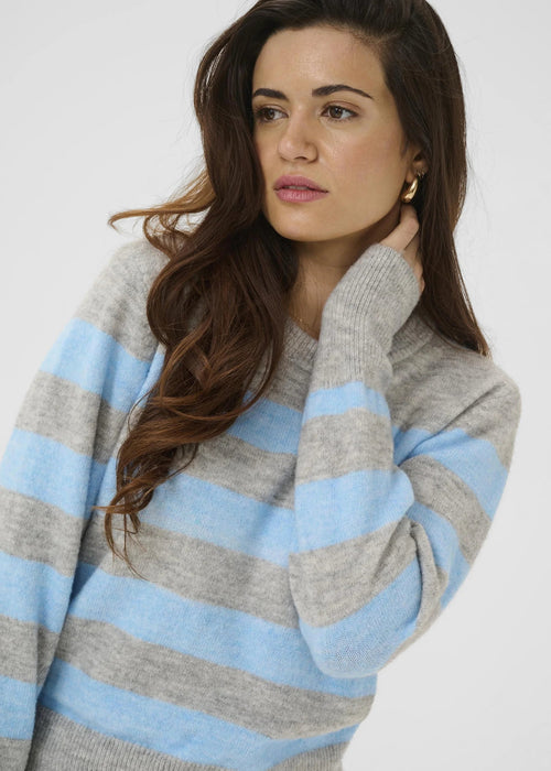 Woman wearing a grey and blue striped pullover on a white background