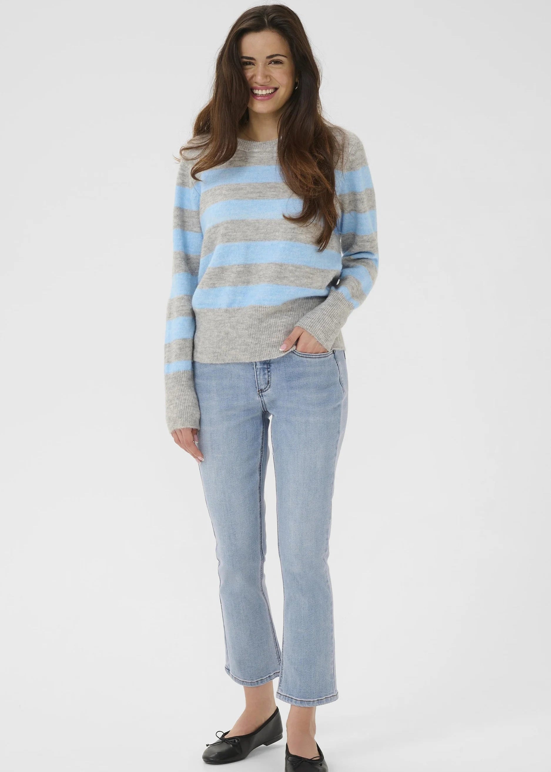 Woman wearing a grey and blue striped pullover on a white background
