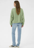 Woman wearing a green sweatshirt on a white background