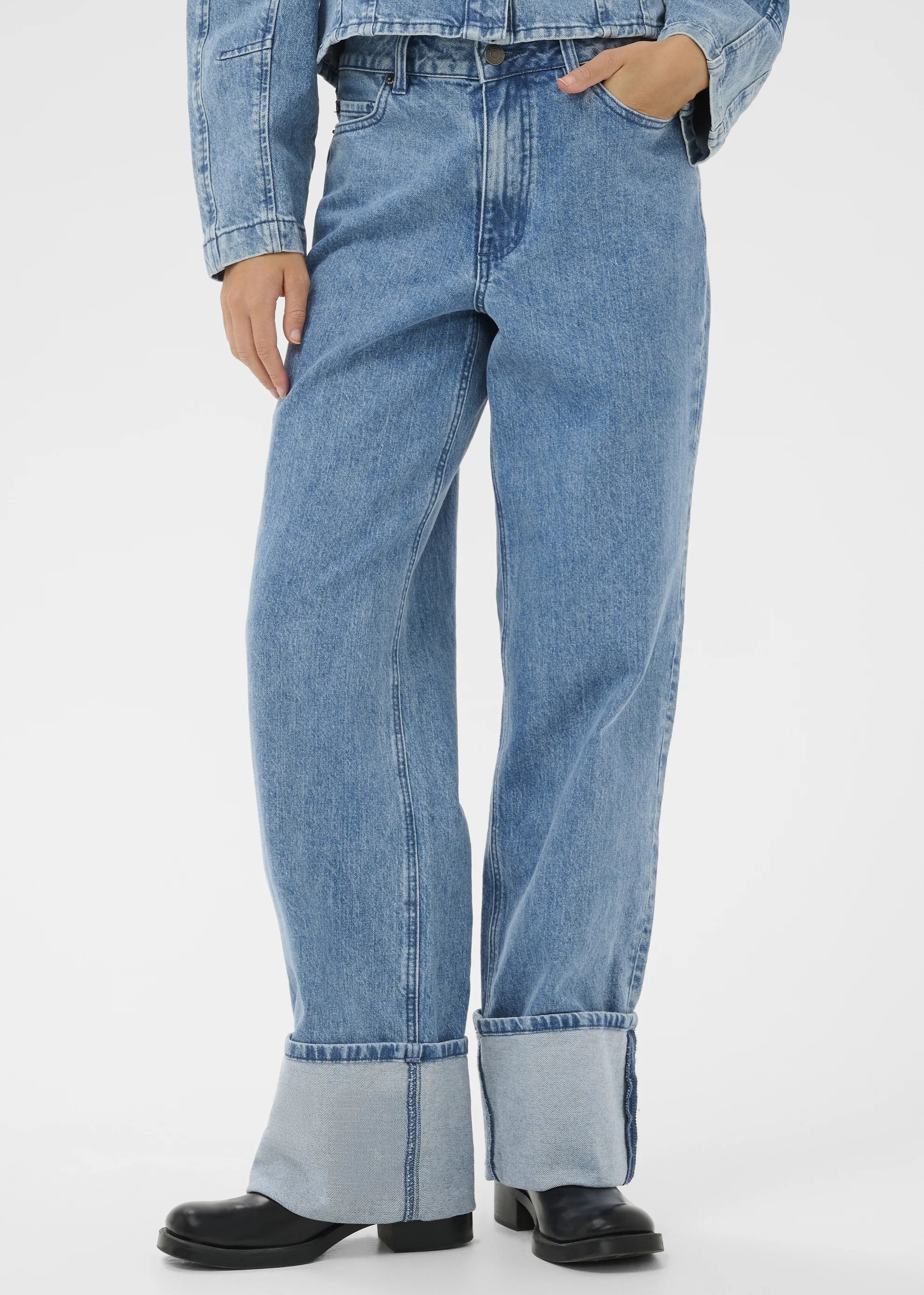Woman wearing light blue jeans with a white background