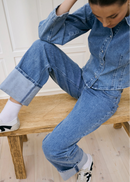 Woman wearing light blue jeans with a white background