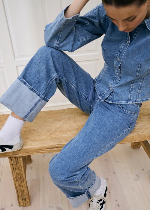 Woman wearing light blue jeans with a white background
