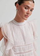 Woman wearing a white blouse with lace details on a light background