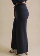 Navy blue wide-leg pants worn by a person on a beige background