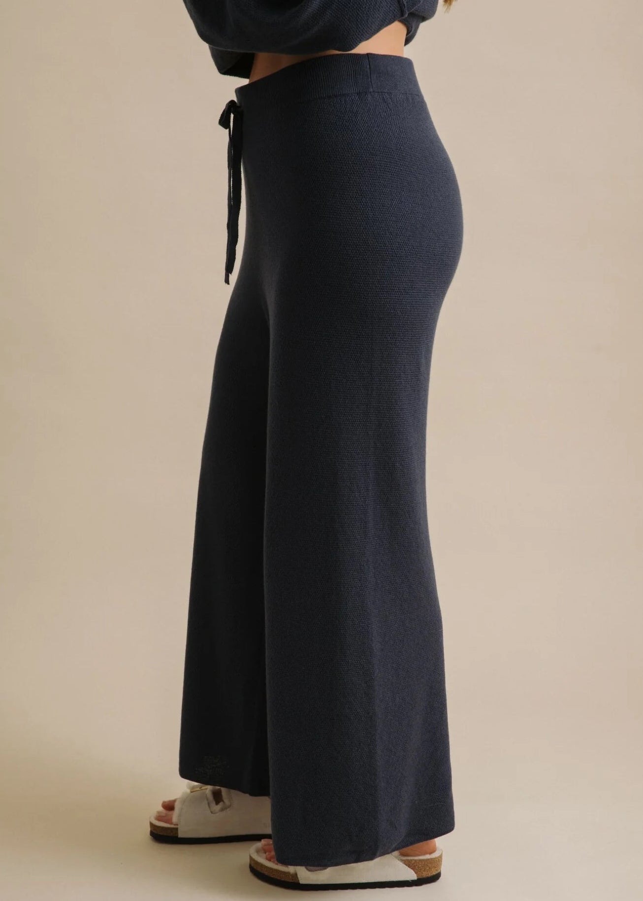 Navy blue wide-leg pants worn by a person on a beige background