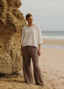 Woman modelling whit top and brown pant at beach