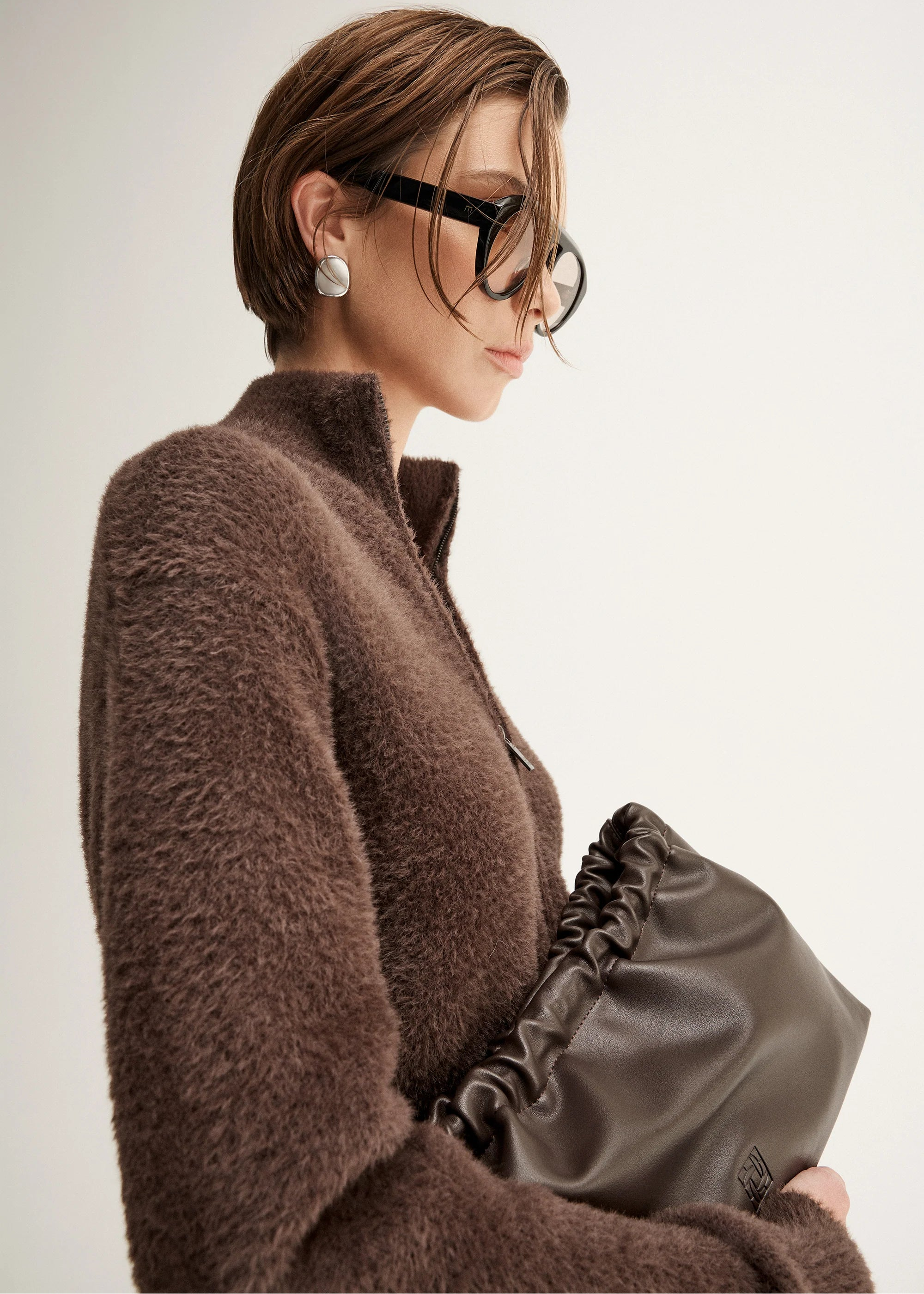 Woman wearing a brown fuzzy cardigan  on a plain background