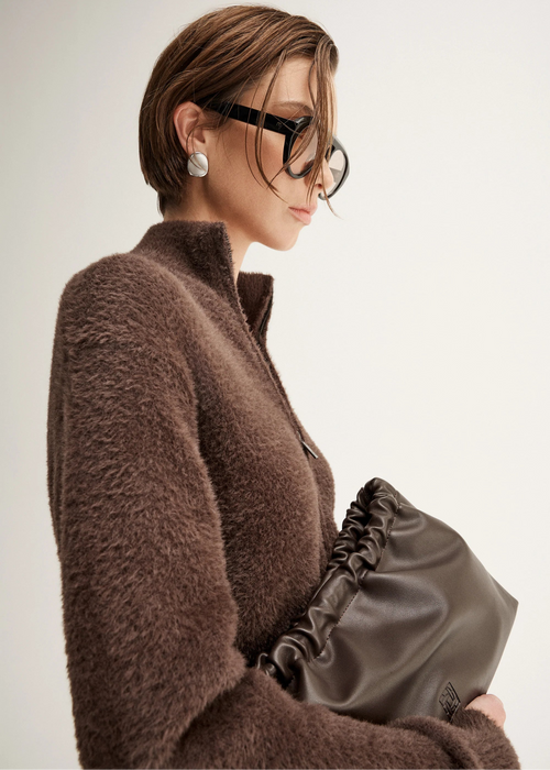 Woman wearing a brown fuzzy cardigan  on a plain background
