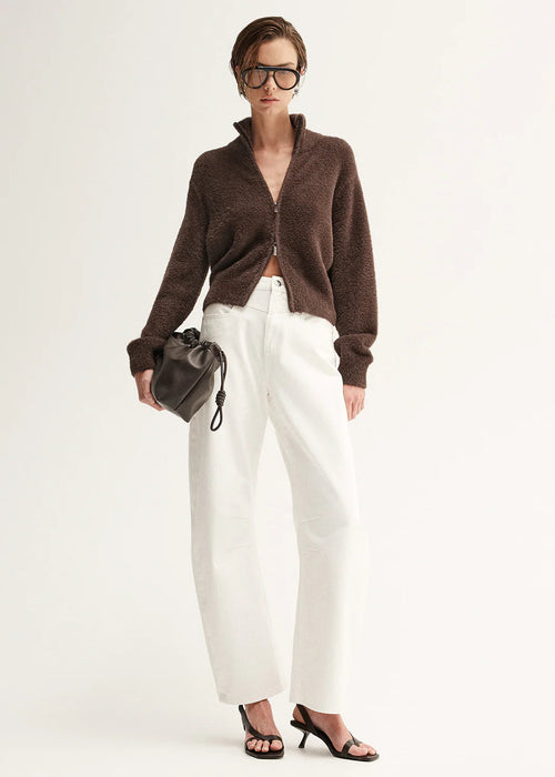 Woman wearing a brown fuzzy cardigan  on a plain background