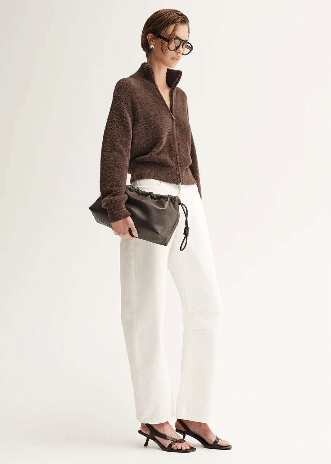 Woman wearing a brown fuzzy cardigan  on a plain background