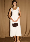 Women modelling a white midi dress on a gold curtain background