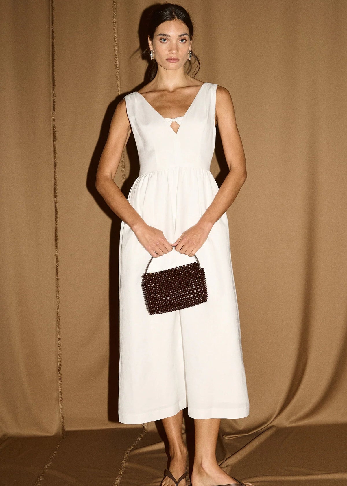 Women modelling a white midi dress on a gold curtain background