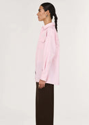 Woman wearing a light pink shirt and black pants on a white background