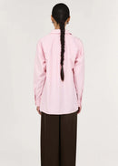Person wearing a pink shirt and brown pants on a white background