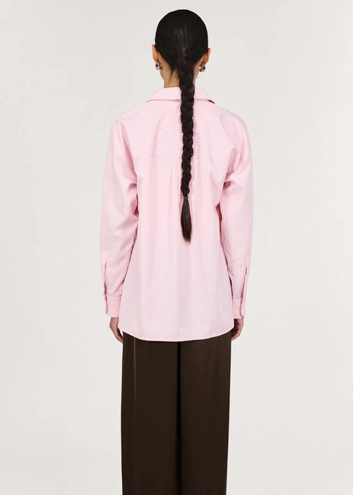 Person wearing a pink shirt and brown pants on a white background