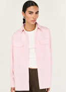 Person wearing a pink shirt over a white top with brown pants on a white background