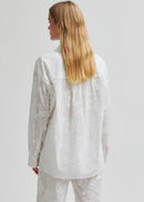 Woman wearing a white button-up shirt and pants on a plain background