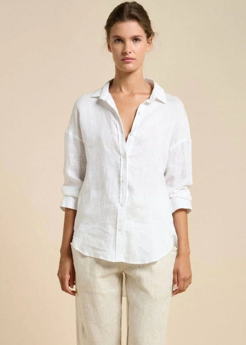 Woman wearing a white shirt and beige pants against a beige background