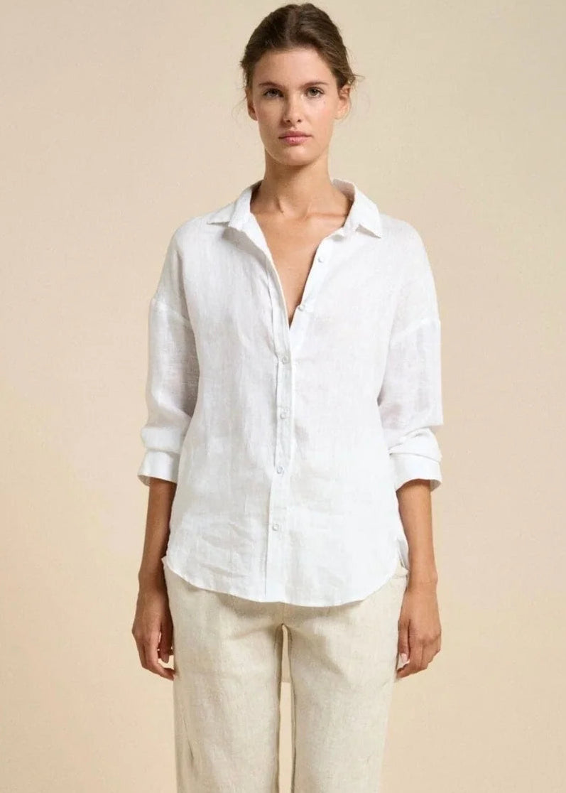 Woman wearing a white shirt and beige pants against a beige background