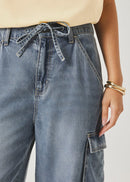 Person wearing blue denim cargo pants with a neutral background