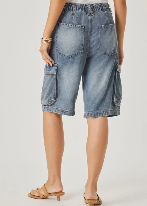 Person wearing blue denim cargo pants with a neutral background