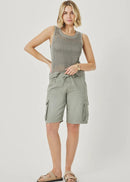 Woman wearing a sleeveless patterned top and cargo shorts on a plain background