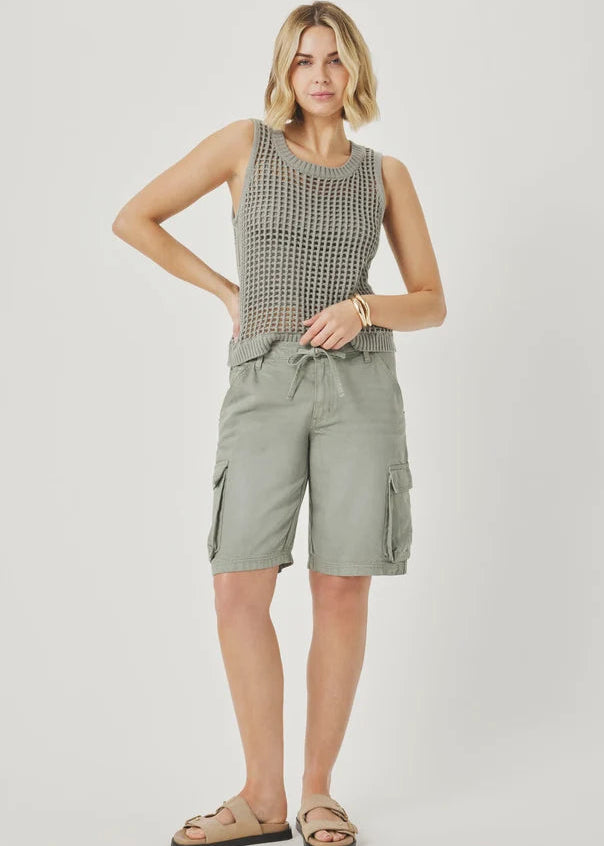 Woman wearing a sleeveless patterned top and cargo shorts on a plain background