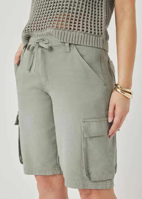 Person wearing light green cargo shorts with a neutral background