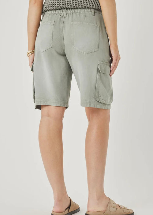 Person wearing light green cargo shorts with a neutral background