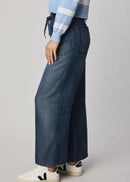 Woman wearing a blue and white striped sweater and wide-leg jeans on a grey background