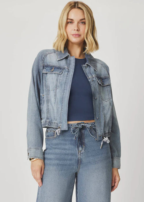 Woman wearing a denim jacket and jeans on a plain background