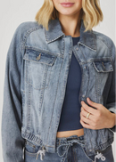 Woman wearing a denim jacket and jeans on a plain background