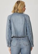Woman wearing a denim jacket and jeans on a plain background