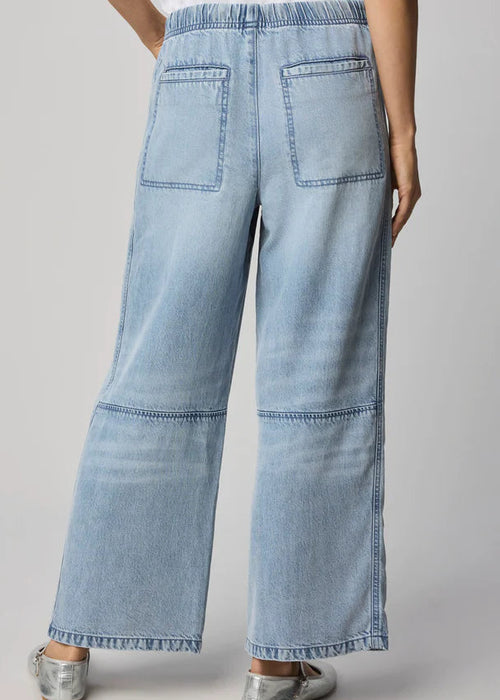 Woman wearing a white t-shirt and light blue jeans on a grey background