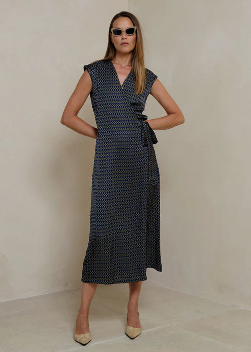 Woman wearing a black patterned dress on a light background