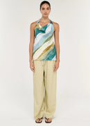 Women wearing halter neck green top with beige pants on white background