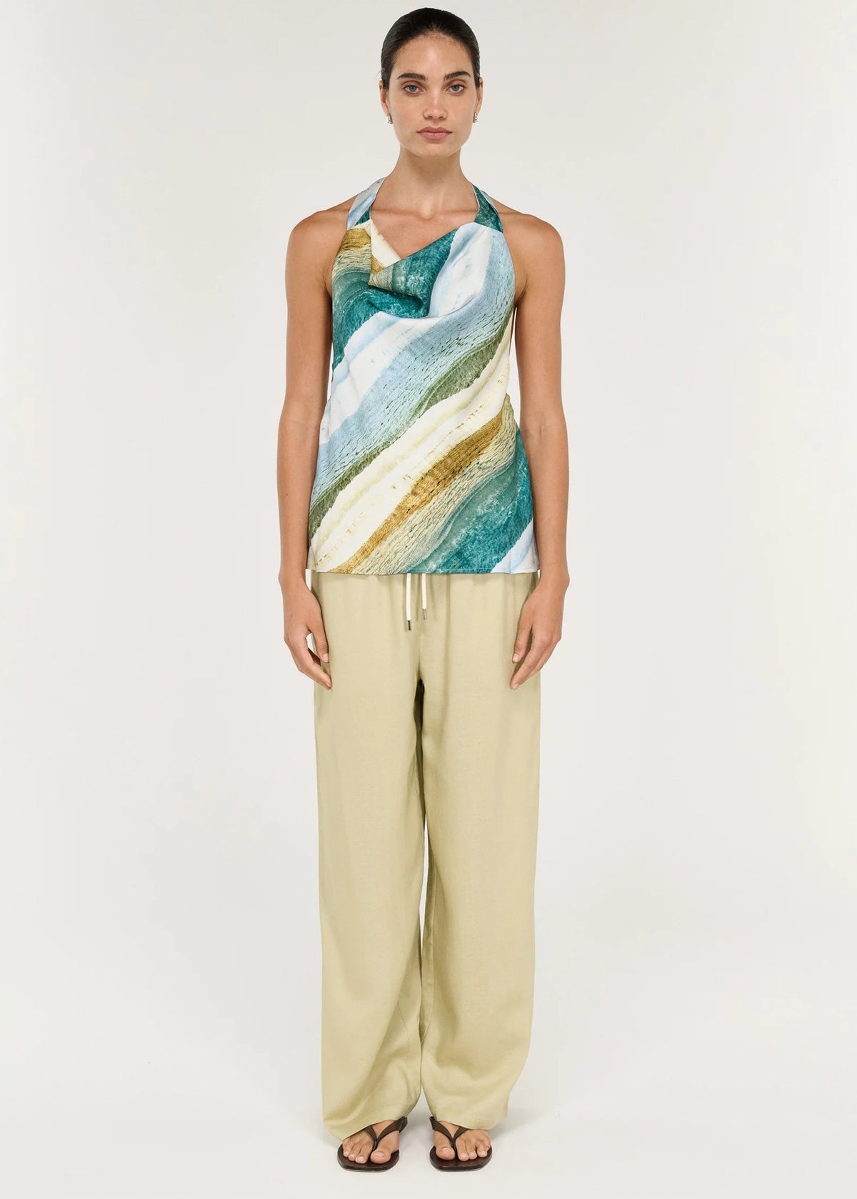 Women wearing halter neck green top with beige pants on white background