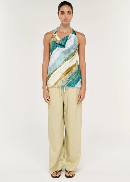 Women wearing halter neck green top with beige pants on white background