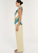 Women wearing halter neck green top with beige pants on white background