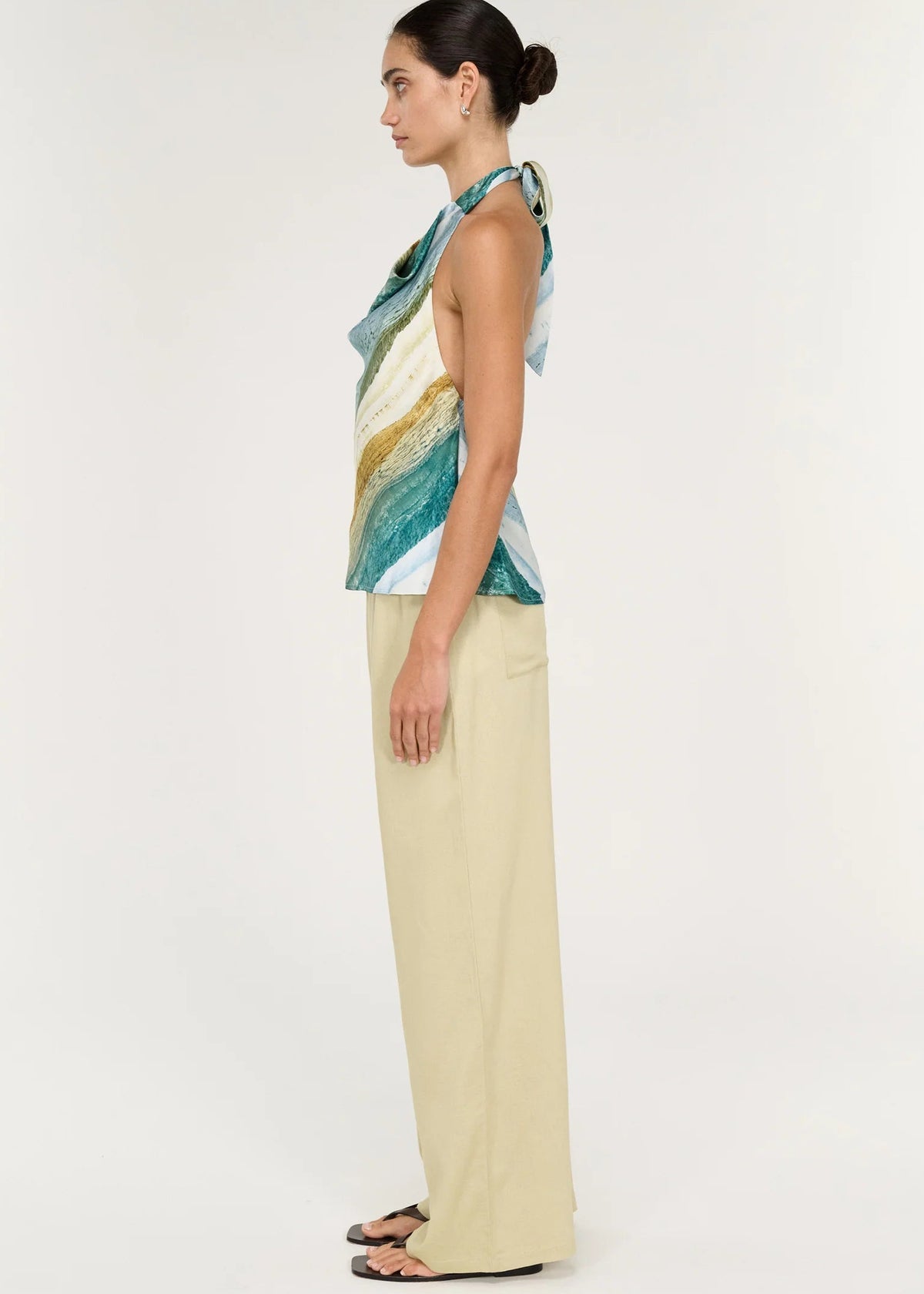 Women wearing halter neck green top with beige pants on white background