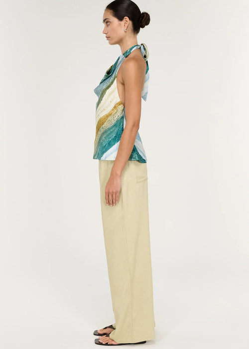 Women wearing halter neck green top with beige pants on white background