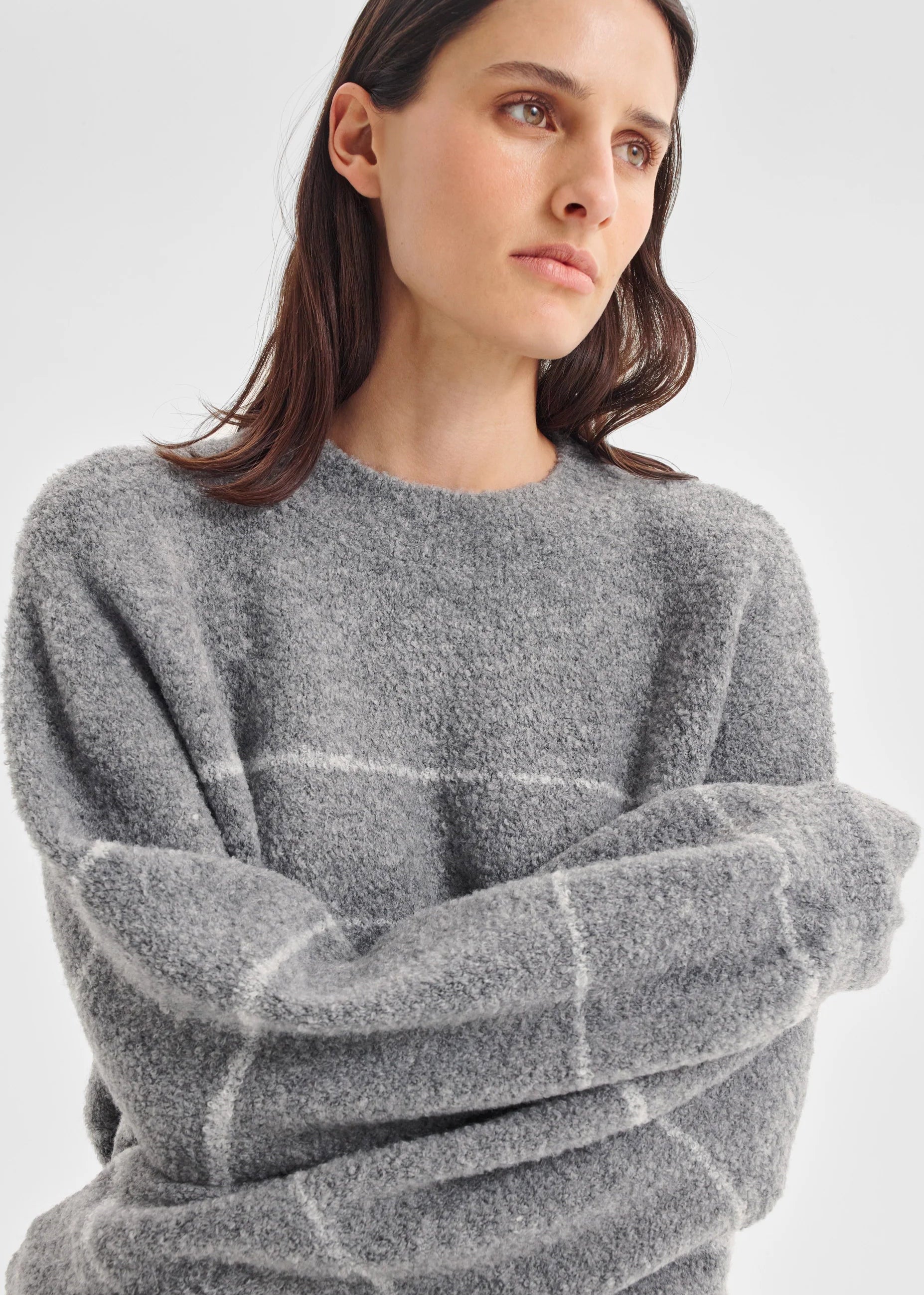 Woman wearing a grey sweater on a white background