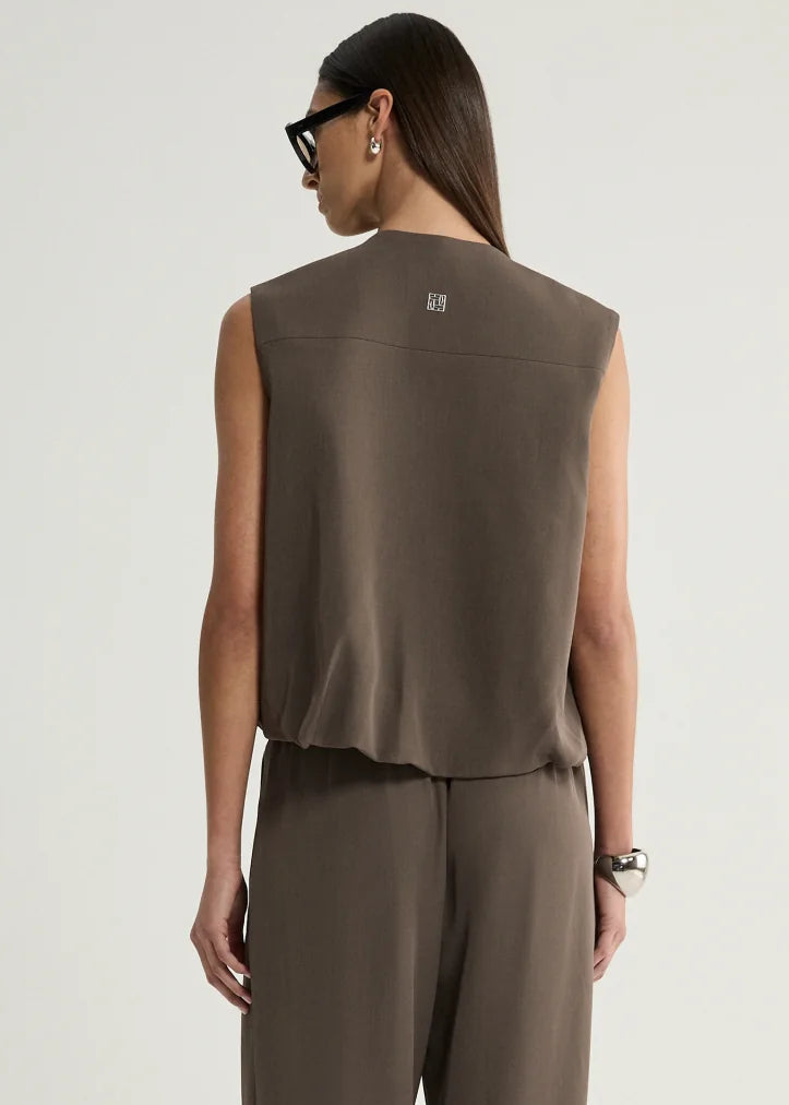 A model shown from the back wearing a sleeveless taupe-brown top and matching wide-leg trousers against a plain light grey studio background.