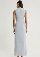A woman viewed from the back wearing a sleeveless, floor-length light blue dress against a plain light grey studio background.