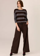 Woman wearing a striped sweater and wide-leg pants on a plain background