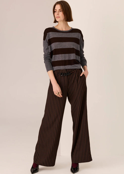 Woman wearing a striped sweater and wide-leg pants on a plain background