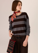 Woman wearing a striped sweater and wide-leg pants on a plain background