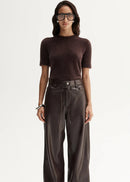 Woman wearing a brown top and wide-leg pants on a white background
